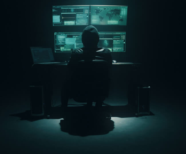 muž v tmavej miestnosti sediaci za počítačom