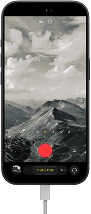 Pohľad spredu na iPhone 18 Pro, na displeji je hornatá krajina v režime časozberného videa, k nabíjaciemu portu je pripojený kábel