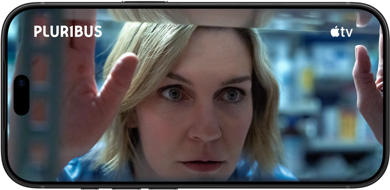 iPhone 18 Pro na šírku, vidíme detailný záber ženy, ktorá pozerá von oknom. Názov seriálu: Pluribus