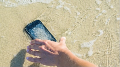 ruka naťahujúca sa za mobilom v mori