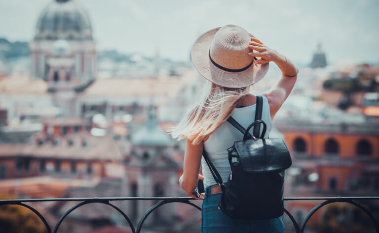 žena s klobúkom pozerajúca sa na mesto