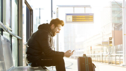 muž s mobilom čakajúci na vlak