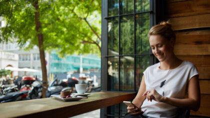 žena s mobilom v kaviarni