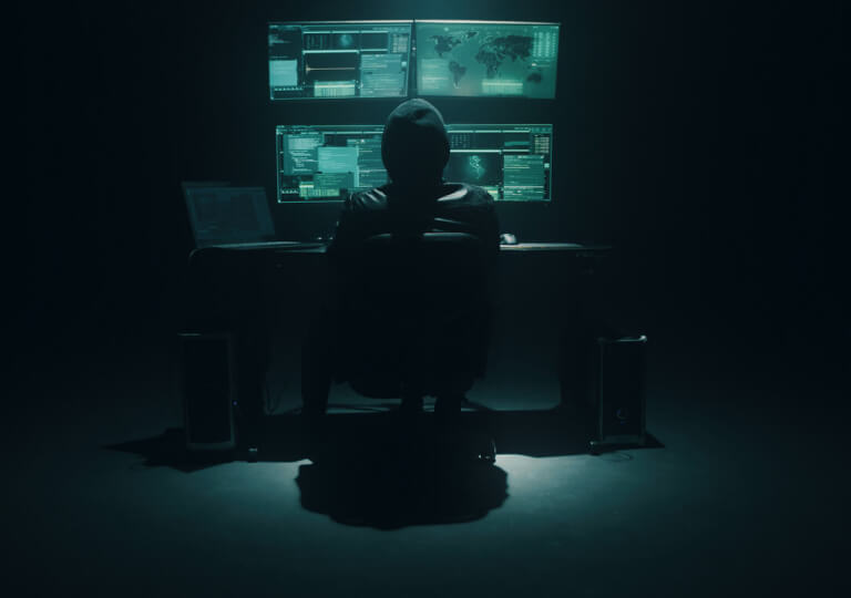 muž v tmavej miestnosti sediaci za počítačom
