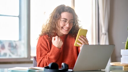 žena vyjadrujúca radosť s mobilom v ruke