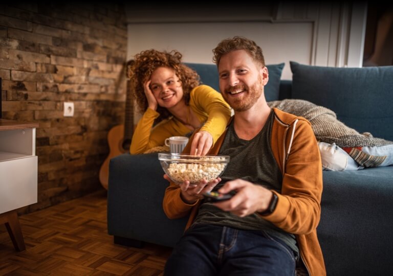 muž so ženou jedia pukance a pozerajú televízor