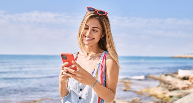 žena na pláži s mobilom