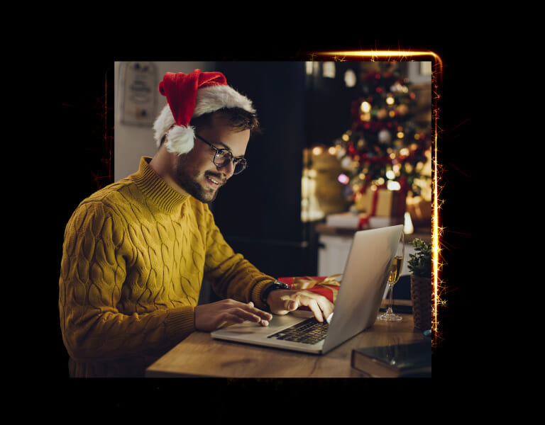 človek vo vianočnej čiapke pri notebooku